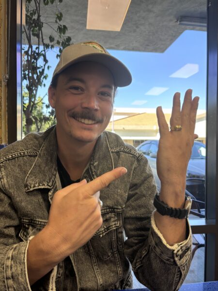A client smiling and pointing at the recovered ring back on his finger
